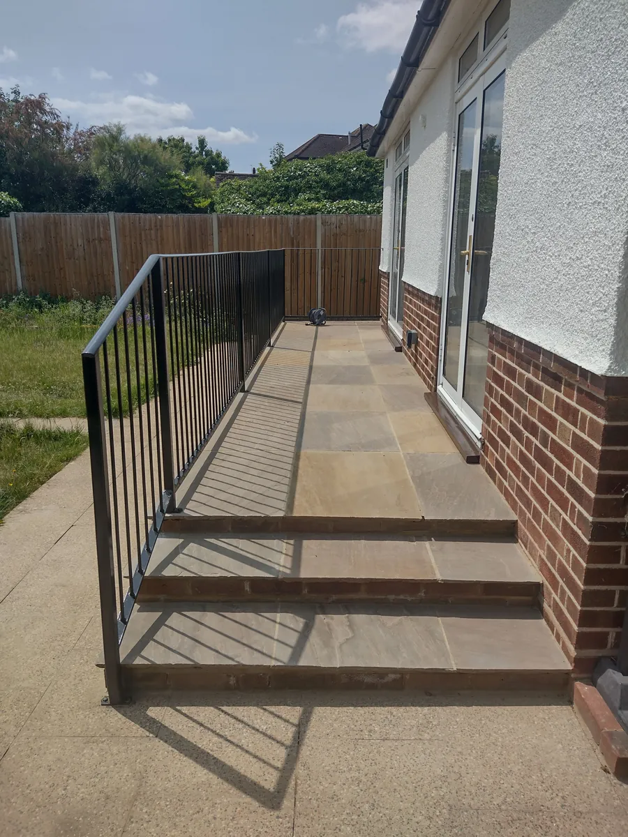 Paved steps with black metal railings leading to a patio